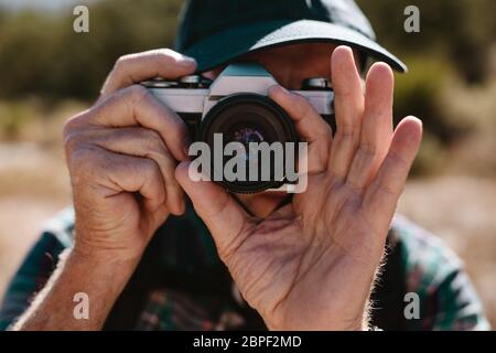 Gros plan d'un homme expérimenté qui photographie avec un appareil photo numérique. Homme à la retraite prenant quelques photos pendant un voyage de randonnée. Banque D'Images