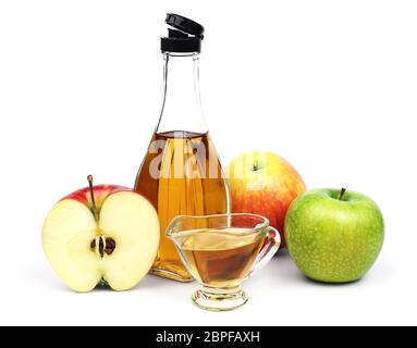 La bouteille transparente et pleine tasse de vinaigre de cidre de pomme et quelques variétés différentes de pommes isolées sur fond blanc. Banque D'Images