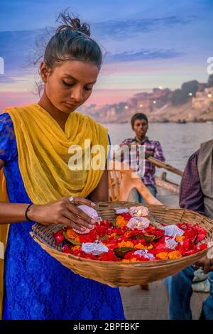 Varanasi, Inde - 11 novembre 2015. Une jeune femme indienne vend des fleurs et des bougies sur un bateau d'excursion au coucher du soleil sur le fleuve Ganges pendant le festival Diwali. Banque D'Images