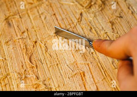 Les copeaux de bois et les couteaux se situent sur une planche en bois close-up. Banque D'Images