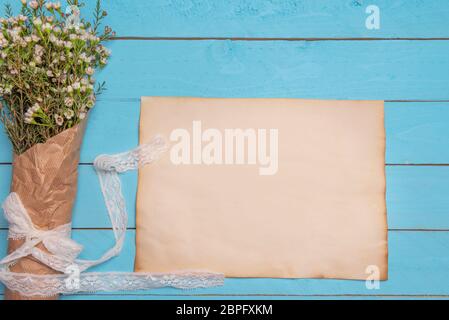 Mise à plat avec l'image de vierge du papier et un bouquet de fleurs blanches sur une table en bois bleu Banque D'Images