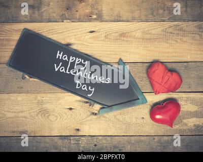 Deux coeurs rouges avec un tableau sur un fond de bois, Happy Valentines Day sur le tableau Banque D'Images