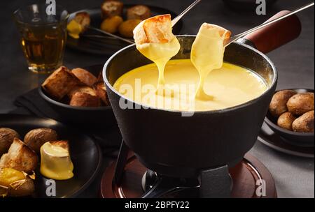 C'est en puisant dans une fondue au fromage gastronomique avec des croûtons sur fourches dans un repas traditionnel Suisse Banque D'Images