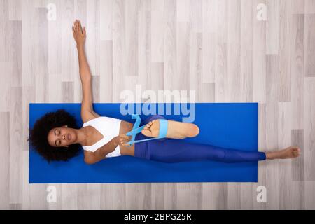 African Woman Stretching Exercice avec ceinture de Yoga tout en faisant l'exercice sur tapis de Fitness Banque D'Images