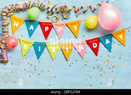 Joyeux anniversaire bunting contexte avec des drapeaux triangulaires, ballons, banderoles et parti les confettis sur un fond de bois bleu with copy space Banque D'Images
