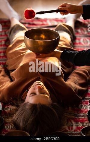 Femme faisant massage relaxant, méditation, thérapie sonore avec des bols de chant tibétien. Soulagement de stress. Mise au point sélective. Vue de dessus. Banque D'Images