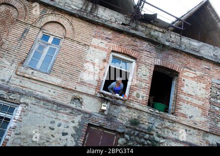 Une femme regarde par sa fenêtre pour avoir une aconversation avec un passant à Telavi, la région viticole de Kakheti, République de Géorgie. Banque D'Images