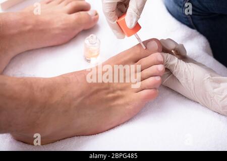 Close-up de manucure ongle main l'application de l'Huile Hydratante pour les pieds de l'Homme Banque D'Images