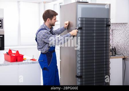 Dans l'ensemble militaire travaillant sur un réfrigérateur à l'aide d'une clé dans la cuisine Banque D'Images