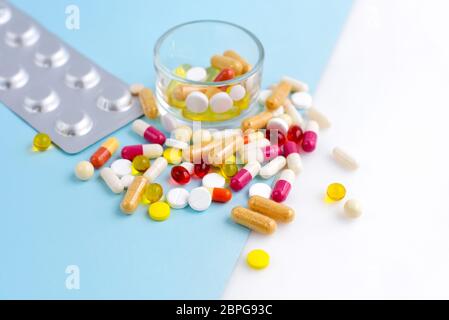 Assortiment de pilules, comprimés et capsules de médecine pharmaceutique sur fond bleu et blanc. Banque D'Images