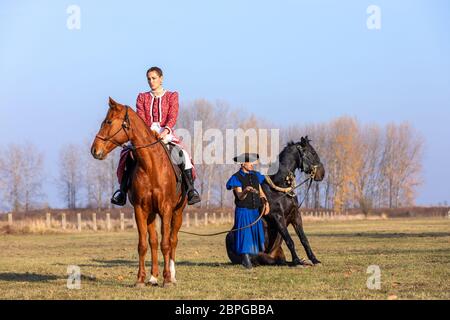 HORTOBAGY, HONGRIE, NOVEMBRE 04. 2018: Csikos hongrois en costume traditionnel folklorique montrant son cheval entraîné. Cheval-homme traditionnel de Hung Banque D'Images