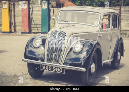 Vue de face d'un véhicule Morris 8 classique, garé à l'extérieur d'un garage vintage, Royaume-Uni. Banque D'Images