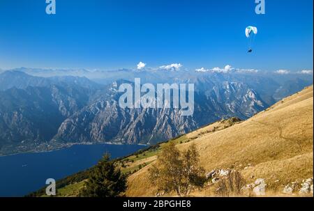 Vue sur les Alpes et un parapente sur le lac de Garde depuis la montagne Monte Baldo, Lombardie, Italie. Banque D'Images