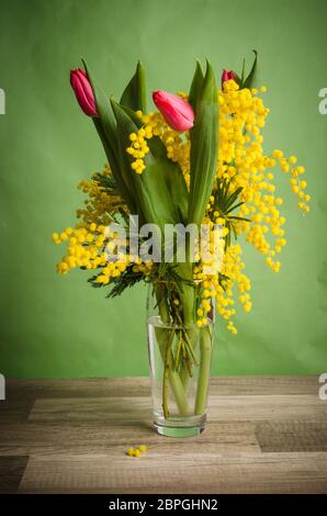 Bouquet de printemps avec mimosa et tulipes dans un vase Banque D'Images