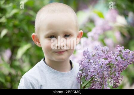 Un enfant dans un lilas. Rire garçon avec un bouquet de fleurs de printemps. Banque D'Images