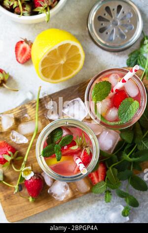 Boisson rafraîchissante en été. Limonade aux fraises fraîches, glace et citrons sur un comptoir en pierre légère. Vue de dessus de l'arrière-plan de la mise à plat Banque D'Images