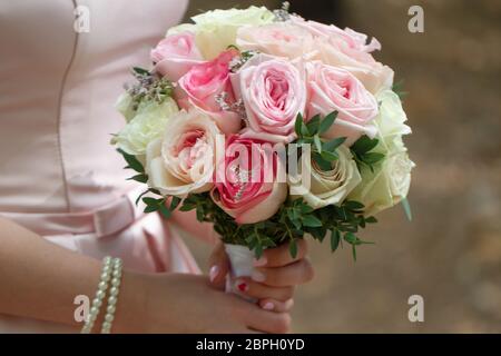 Beau mariage bouquet de roses crème dans les mains de la mariée. Banque D'Images