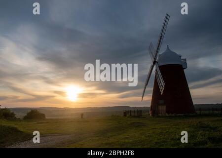Coucher de soleil avec le soleil se glissant vers l'horizon derrière le moulin à vent Halnaker près de Chichester dans West Sussex, le moulin est classé de grade 2 Banque D'Images