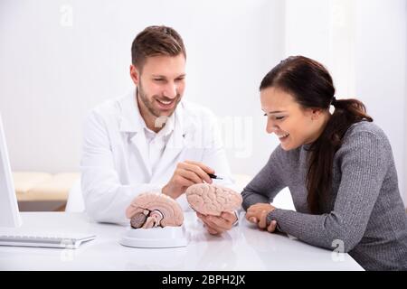 Médecin en expliquant les détails de cerveau humain à Happy Woman with Model Banque D'Images