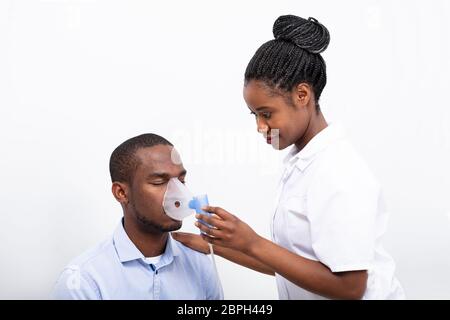 Jeune femme mise sur l'homme Masque inhalateur bouche sur fond blanc Banque D'Images