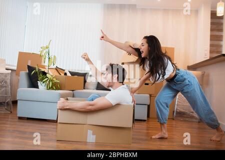 Heureux couple s'amuse avec des boîtes de carton dans la nouvelle maison au jour du déménagement. Banque D'Images