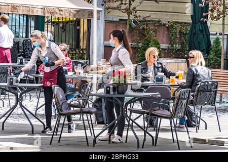 Bar et restaurant en plein air avec clients et serveuse avec masque et gant à Vilnius, capitale lituanienne à transformer en grande ville de café en plein air Banque D'Images