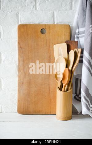 Ustensiles de cuisine simple et rustique en bois ou bambou : couverts, serviette et une planche à découper à l'intérieur de cuisine blanche. Style rustique. Accueil décor de cuisine. Banque D'Images