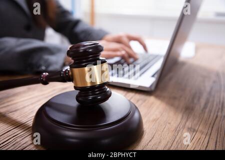 Close-up de juge et Maillet Maillet en face de l'homme à l'aide d'un ordinateur portable sur un bureau en bois Banque D'Images