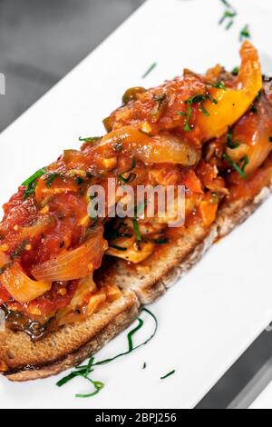 Portuguese caldeirada de peixe tomates poivrons et oignons Ragoût de poisson sur tiborna rustique de style tapas toast Banque D'Images