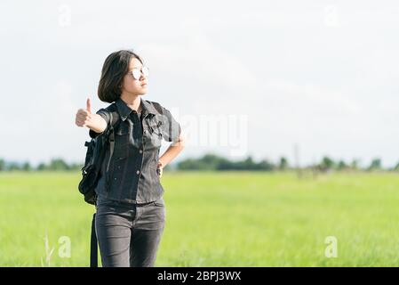 Young Asian woman cheveux courts et portant des lunettes de soleil avec sac à dos randonnée le long d'une route de campagne en Thaïlande Banque D'Images