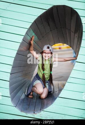 Heureux l'enfant fille dans l'aire de jeux. Petite fille à l'intérieur d'une structure en bois. Focus sélectif. Banque D'Images