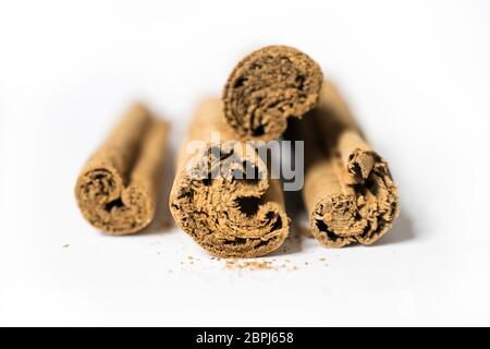 Quatre bâtons de cannelle aromatique sur fond blanc avec des particules de cannelle dispersées autour Banque D'Images