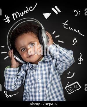 Adorable petit garçon afro-américains avec plaisir à l'écoute de la musique, happy child wearing headphones, portrait sur fond noir avec différentes encore de Banque D'Images