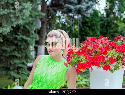 Femme en lunettes de soleil et belle pétunia, belles femmes lumineuses thème d'été et de fleurs Banque D'Images