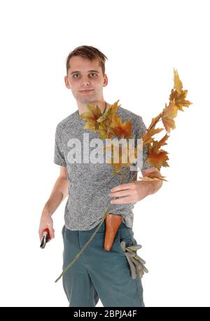 A smiling young debout avec une branche de feuilles d'automne dans sa main et un couteau dans l'autre, isolés pour fond blanc Banque D'Images