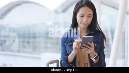 Femme l'utilisation de téléphone mobile dans de l'aéroport de Hong Kong Banque D'Images