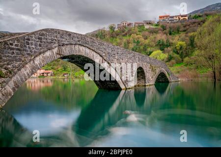 Petit pont en arc de pierre ancienne à Rijeka Crnojevica un jour de pluie, le Monténégro Banque D'Images