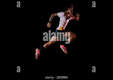 Homme asiatique jeune coureur de sprinter en studio sur fond noir Banque D'Images