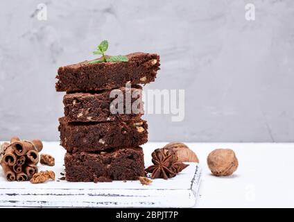 Petits morceaux carrés de brownies au chocolat avec des noix sur une planche de bois blanc, Close up Banque D'Images