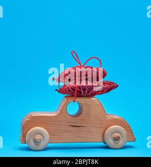 Petite voiture pour enfants en bois en osier porte un cœur rouge sur fond bleu, copy space Banque D'Images