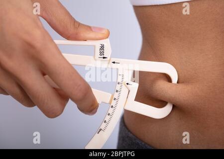 Close-up of a Woman's Hand Gros Ventre de mesure les compas sur fond blanc Banque D'Images