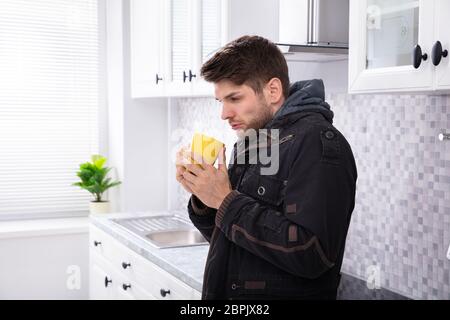 Vue latérale d'homme malade de boire du café dans la cuisine permanent Banque D'Images