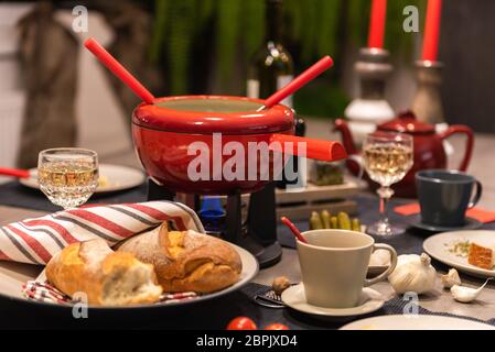 Fondue suisse traditionnelle dans un pot rouge sur le béton d'une table à manger. Banque D'Images