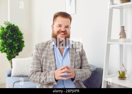 Personnes en ligne regardant la caméra. Un homme souriant barbu regardant la caméra vidéo web chat appel en ligne se réjouit de se faire passer la main à la maison. Banque D'Images