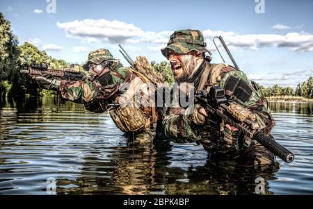 Paire de soldats en action lors d'river raid dans la jungle jusqu'à la dans l'eau et de boue et couvrant les uns les autres Banque D'Images