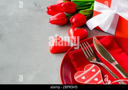 Table de fête pour le jour de Valentine avec boîte-cadeau, des tulipes et des bougies en forme de cœur. Banque D'Images