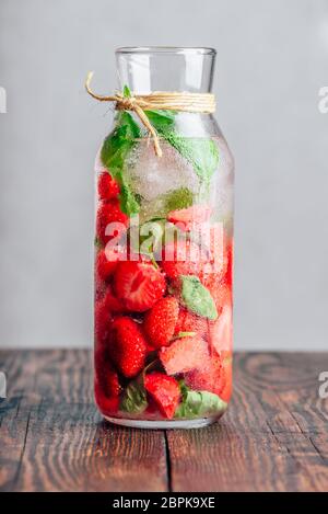 L'eau en bouteille Detox avec des fraises fraîches et de feuilles de basilic. Orientation verticale. Banque D'Images