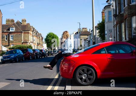 Femme assise sur le coffre d'une Audi rouge Banque D'Images