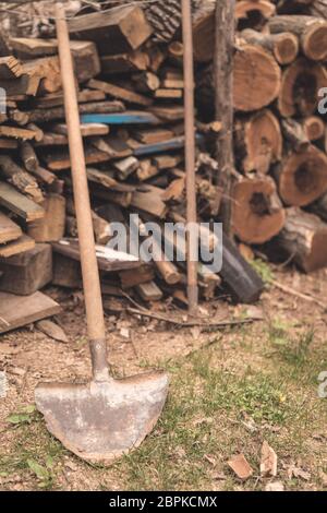 Vieux et rouillé d'une pelle de jardin en face d'un bois de chauffage dans un jardin Banque D'Images