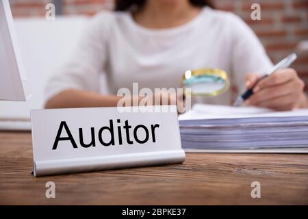 Plaque constructeur avec le titre de vérificateur conservés sur 24 en face de Businesswoman examinant les factures Banque D'Images